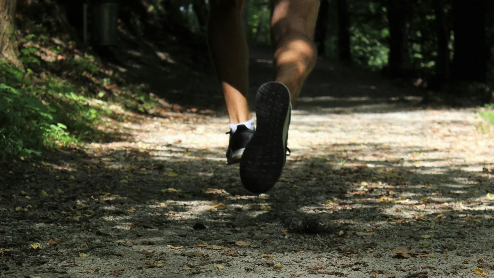 Fötterna av en person som joggar i skogen