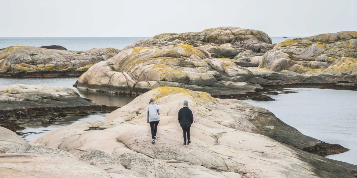 Två personer går på klipporna vid havet